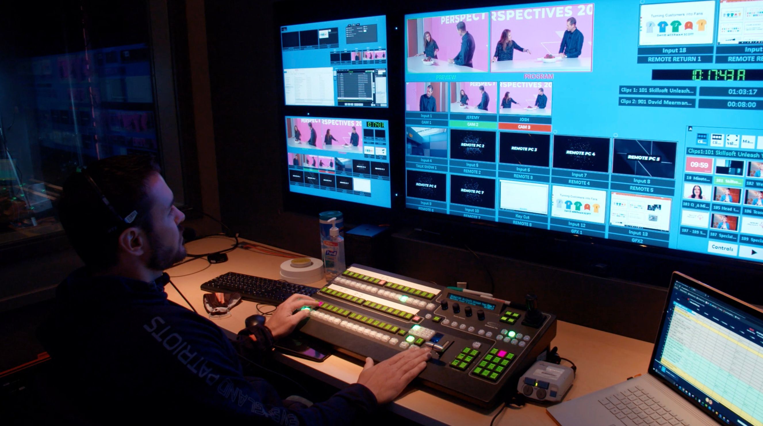Professional virtual control room with multiple monitors displaying live broadcast feeds, audio meters, and production software for event streaming